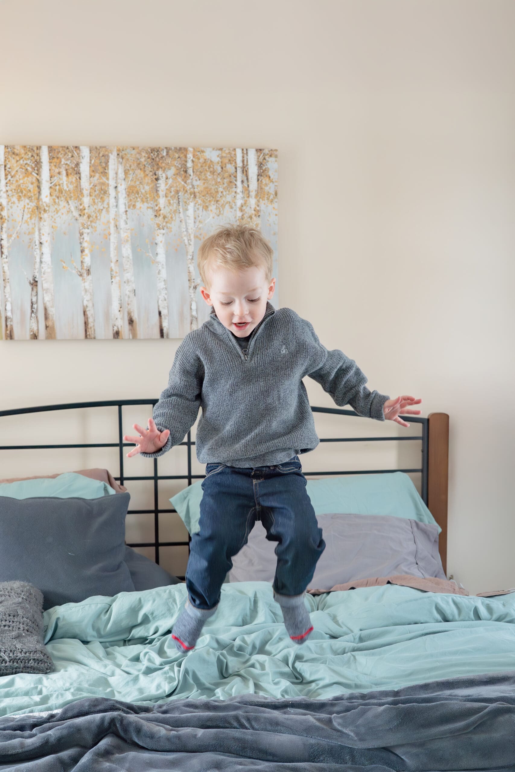 Lifestyle newborn session with toddler jumping on bed — captured by Alliston and Barrie maternity, newborn, and family photographer.