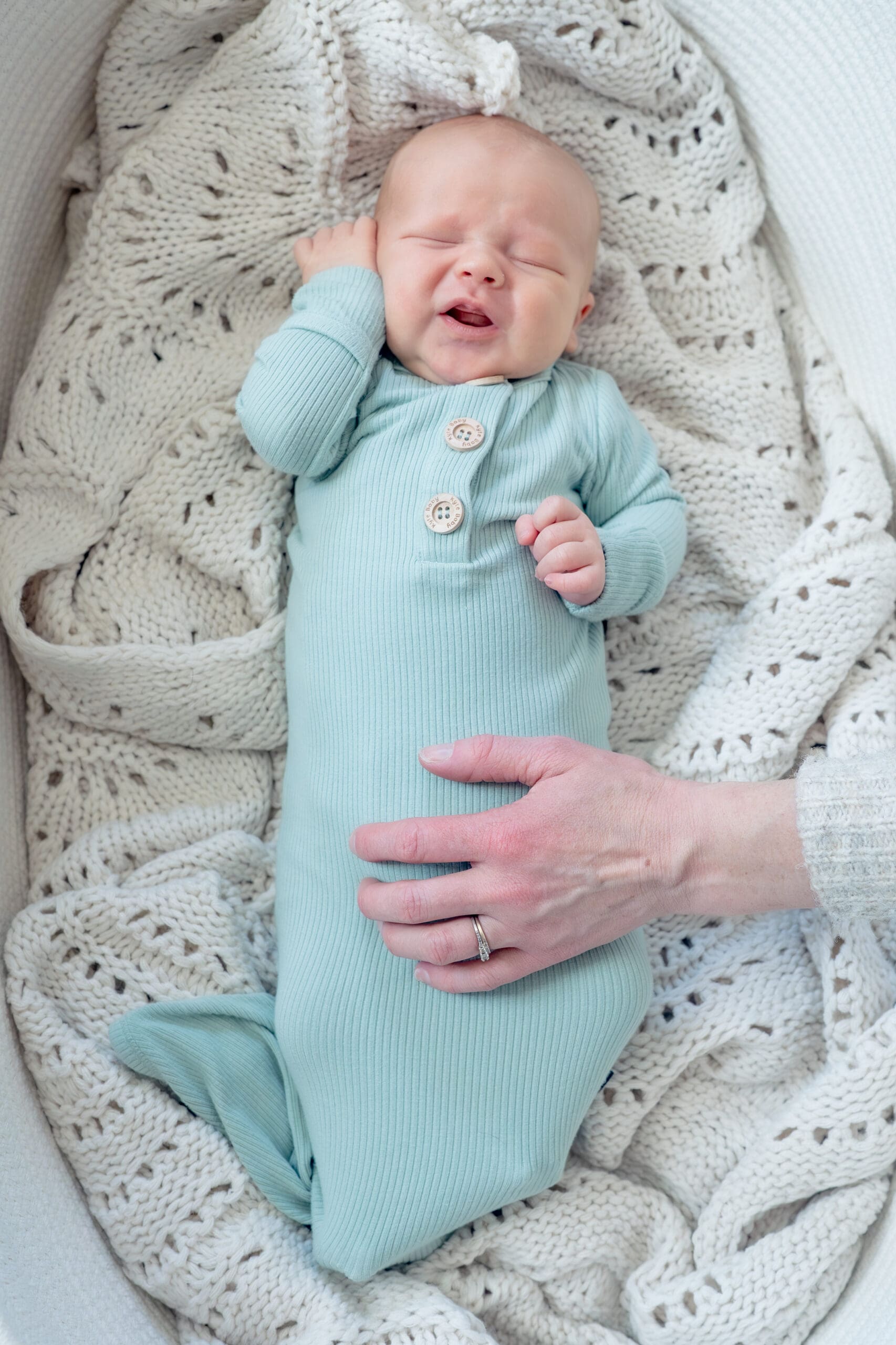 Lifestyle newborn session with baby stretching in basket — captured by Alliston and Barrie maternity, newborn, and family photographer.