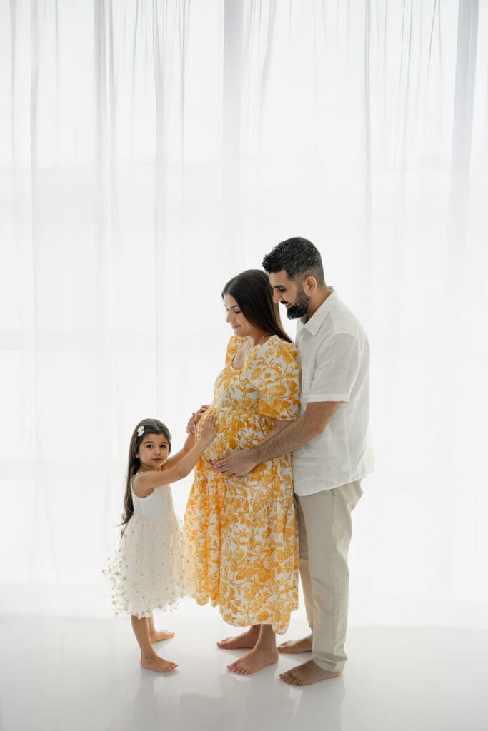 Expecting parents smiling at toddler  during a soft, natural light maternity session — photographed by Alliston and Barrie maternity, newborn, and family photographer.