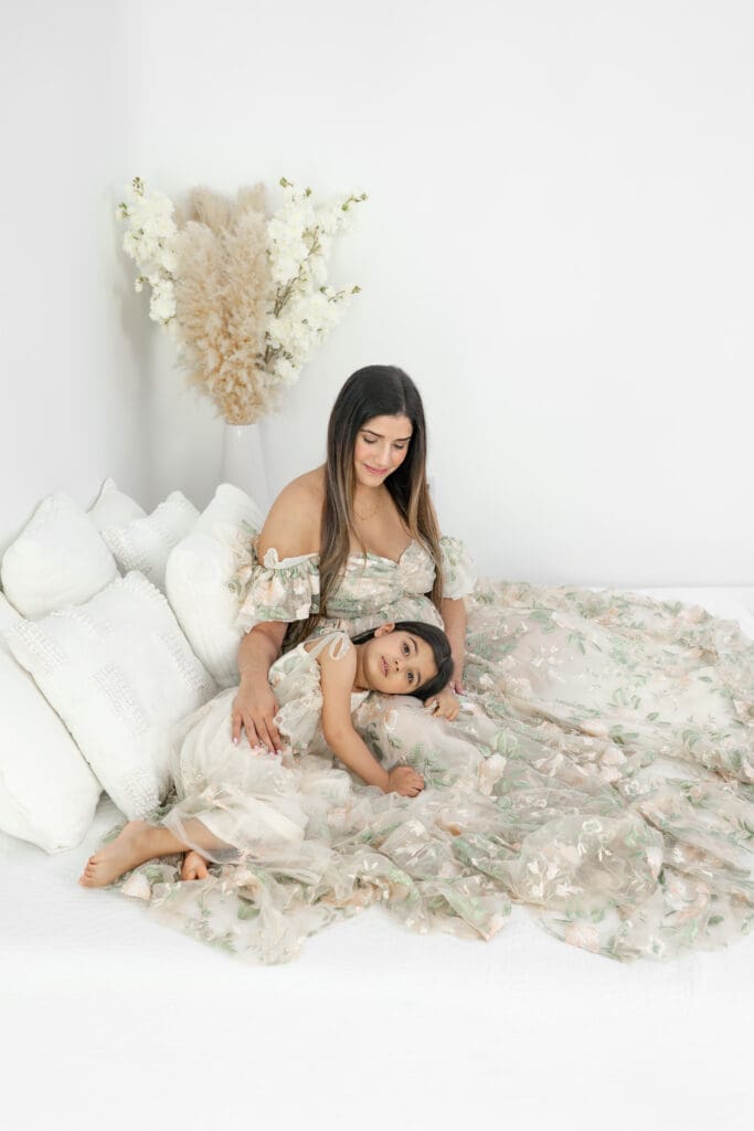 Toddler resting head on the lap of her expecting mom during a soft, natural light maternity session — photographed by Alliston and Barrie maternity, newborn, and family photographer.