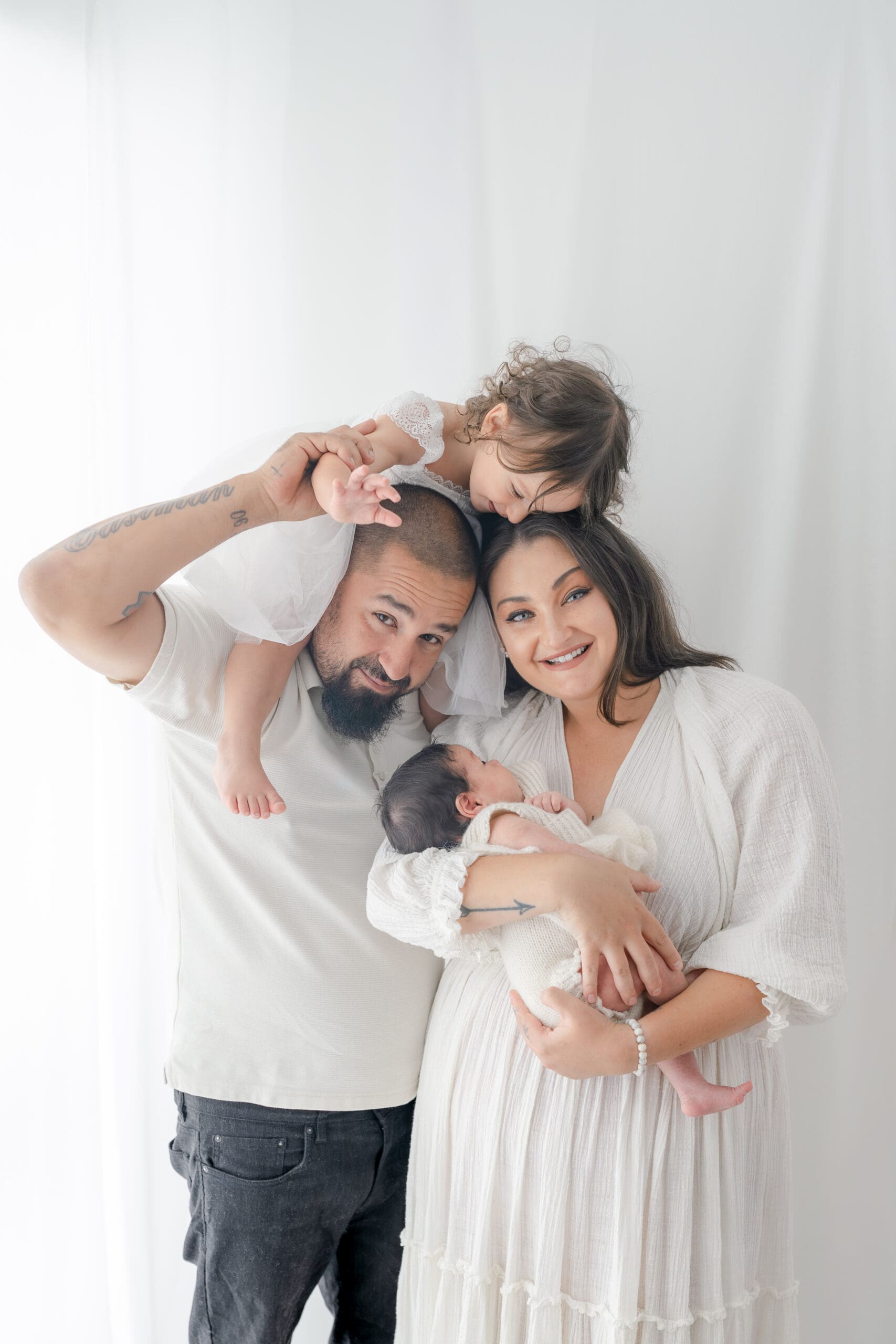 Alliston newborn photographer captures parents and siblings in bright studio setting

