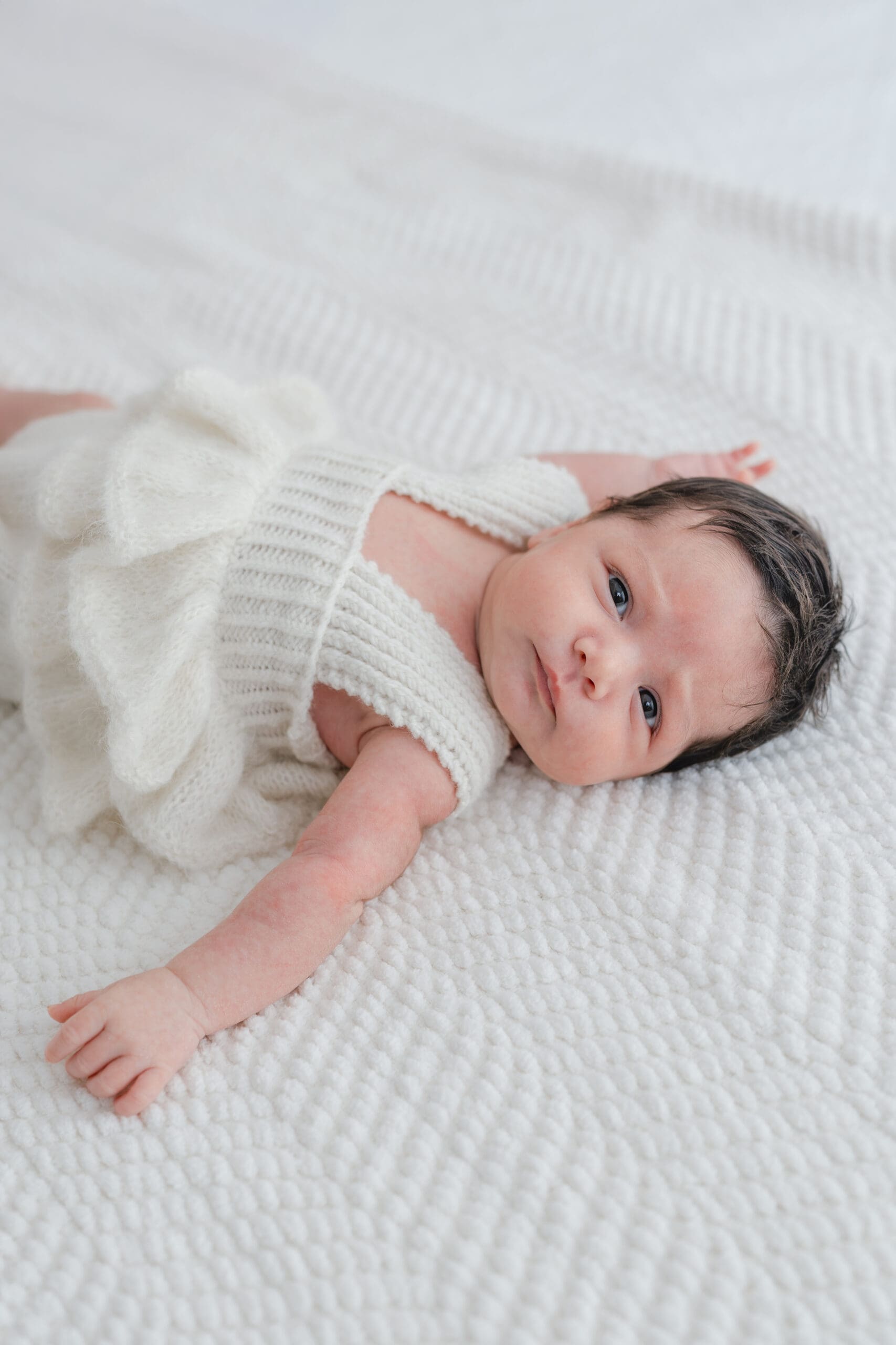 Alliston newborn photographer captures parents and siblings in bright studio setting


