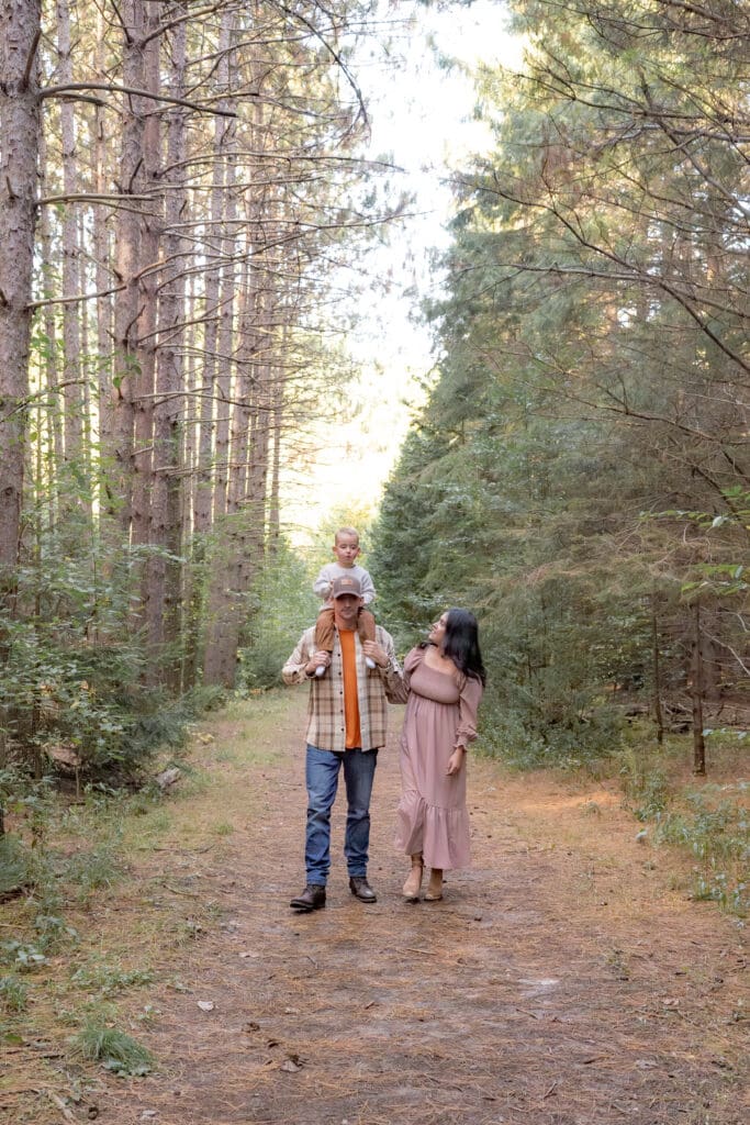 Dad holding toddler on shoulder while mom looks on during family photography session in Bradford
