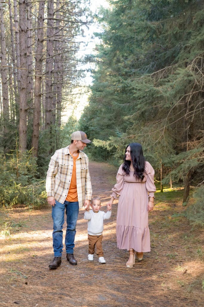 Parents walking trail with toddler between them during family photography session in Bradford