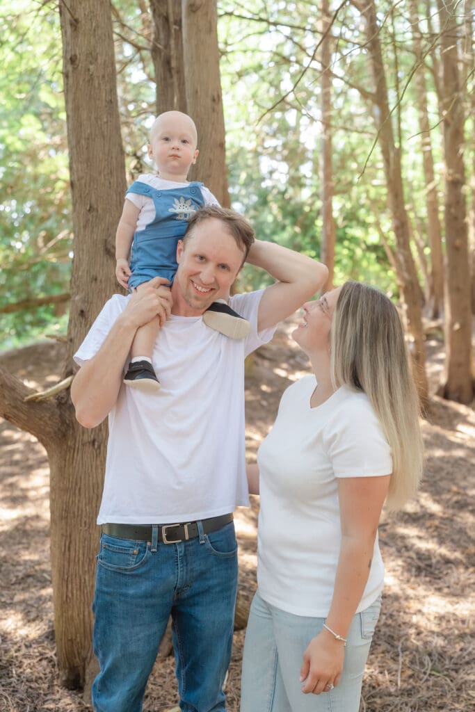 Dad holding toddler on shoulders while mom looks at him during family photography session in Tottenham
